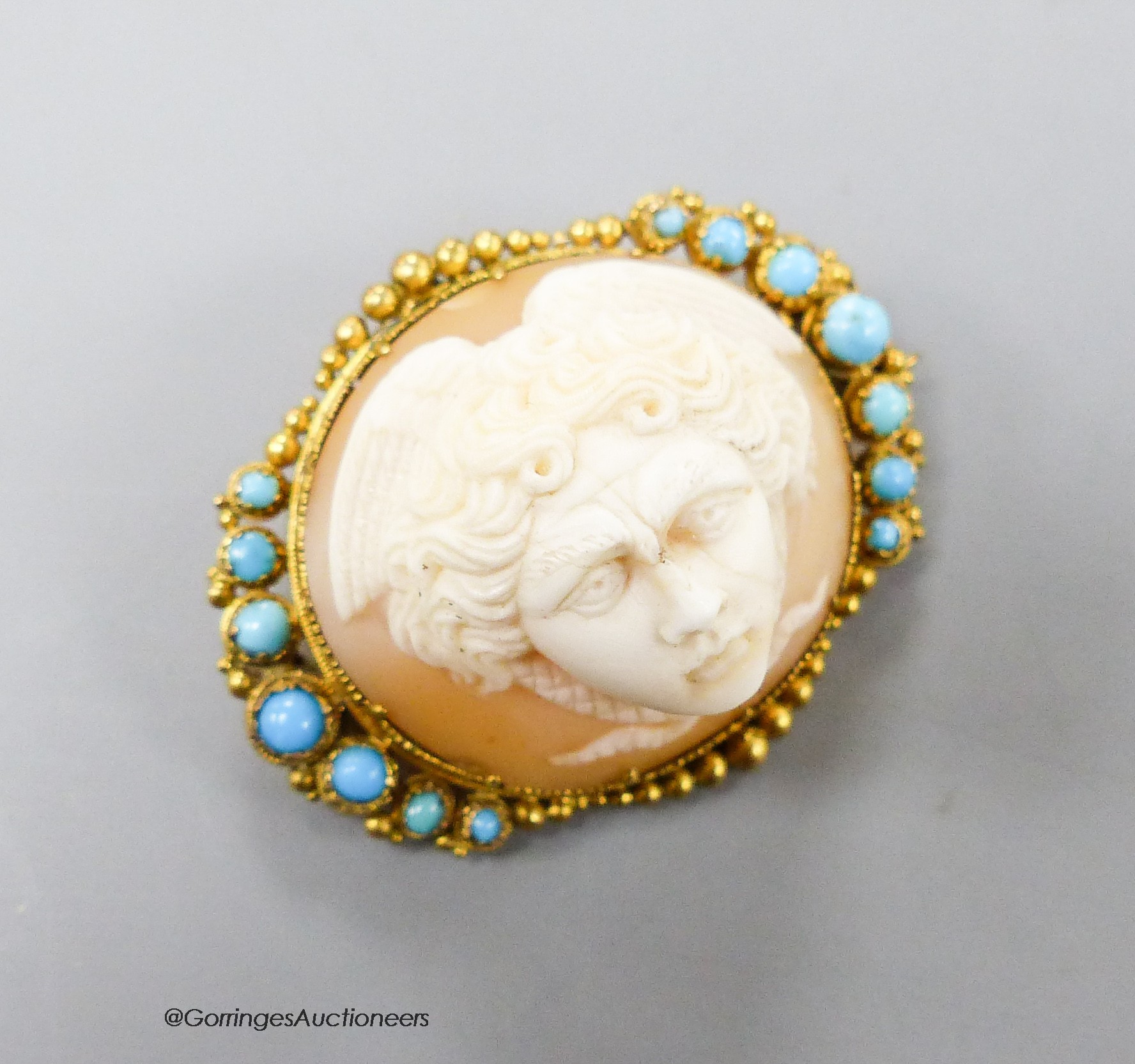 A Victorian yellow metal mounted cameo shell and turquoise set oval brooch, carved with the head of a cherub, 34mm, gross 9.2 grams.